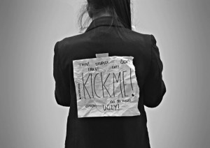 woman with Kick-Me sign in black and white