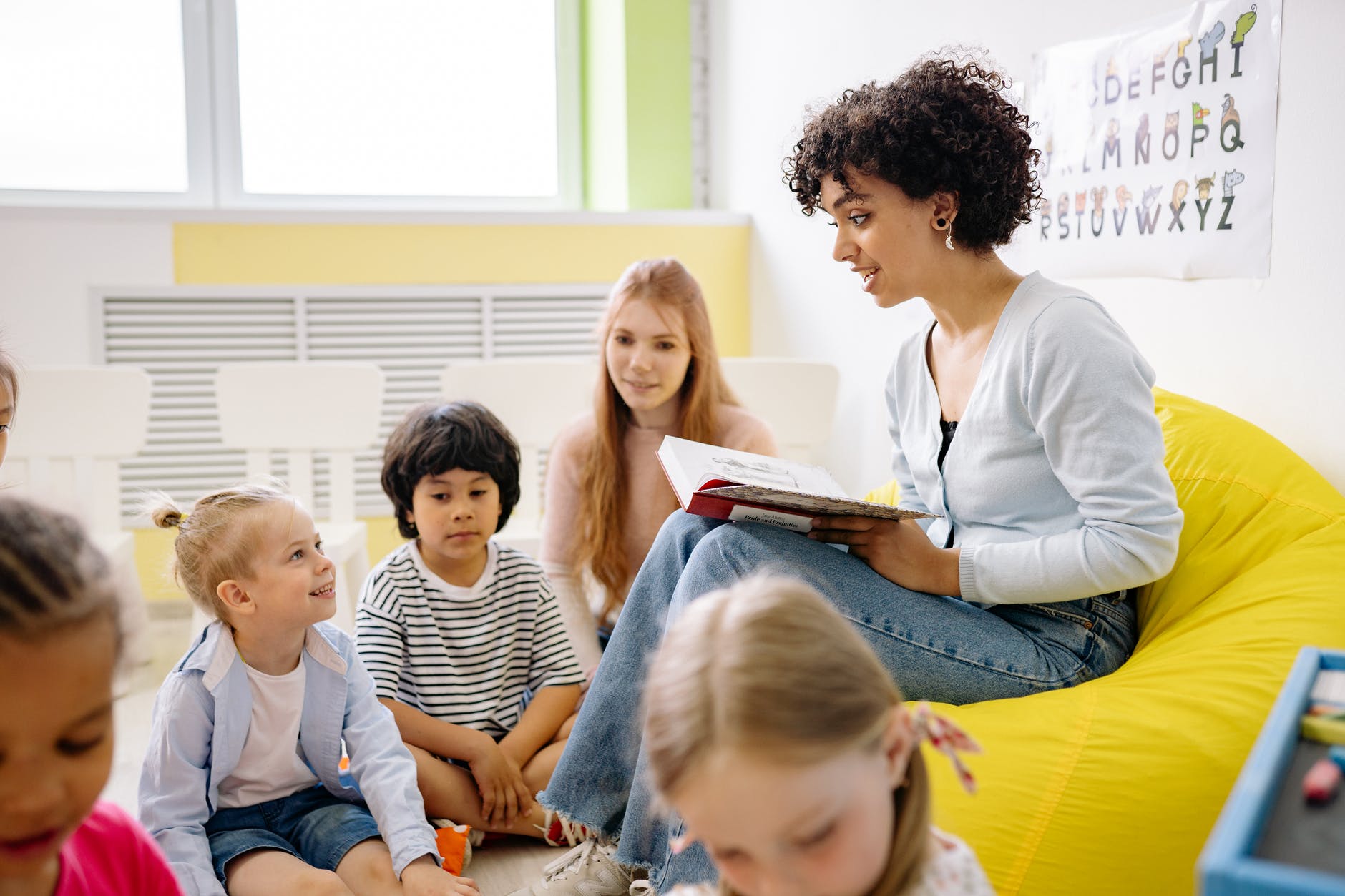 woman sitting and reading to children in classroom