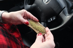 driver rolling a joint in car