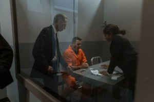 lawyers speaking with male client in interrogation room