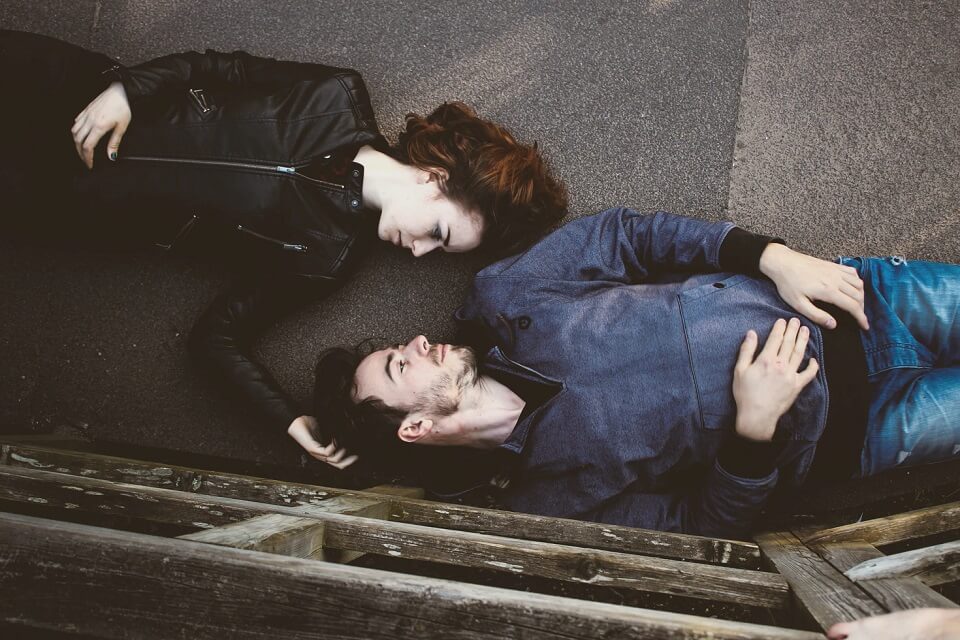 man and woman looking at each other while lying on ground