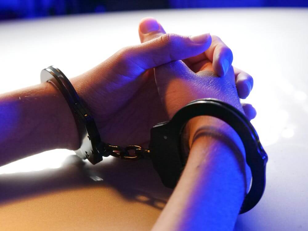 hands in handcuffs resting on table