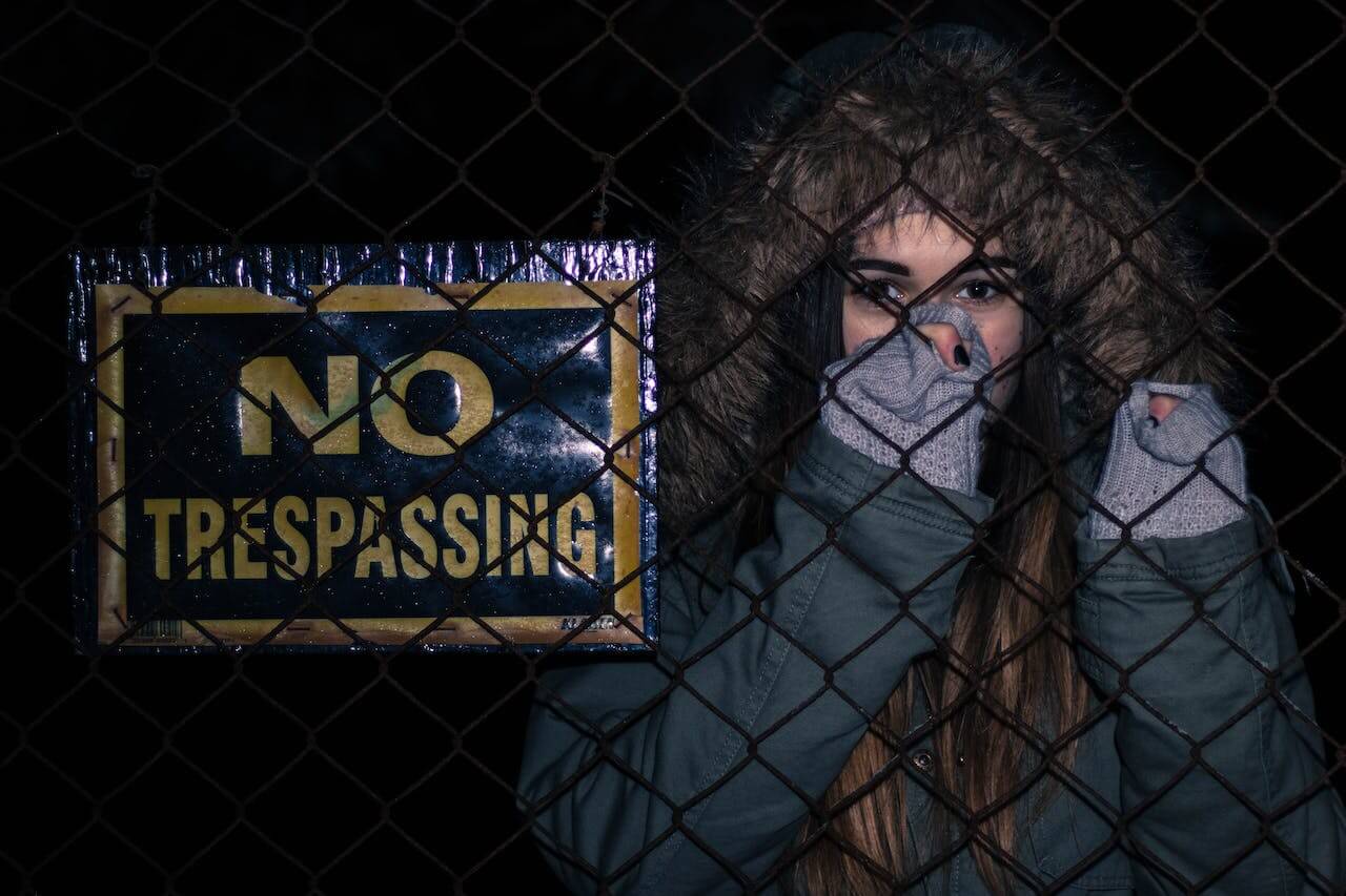 no trespassing sign behind a fence at night
