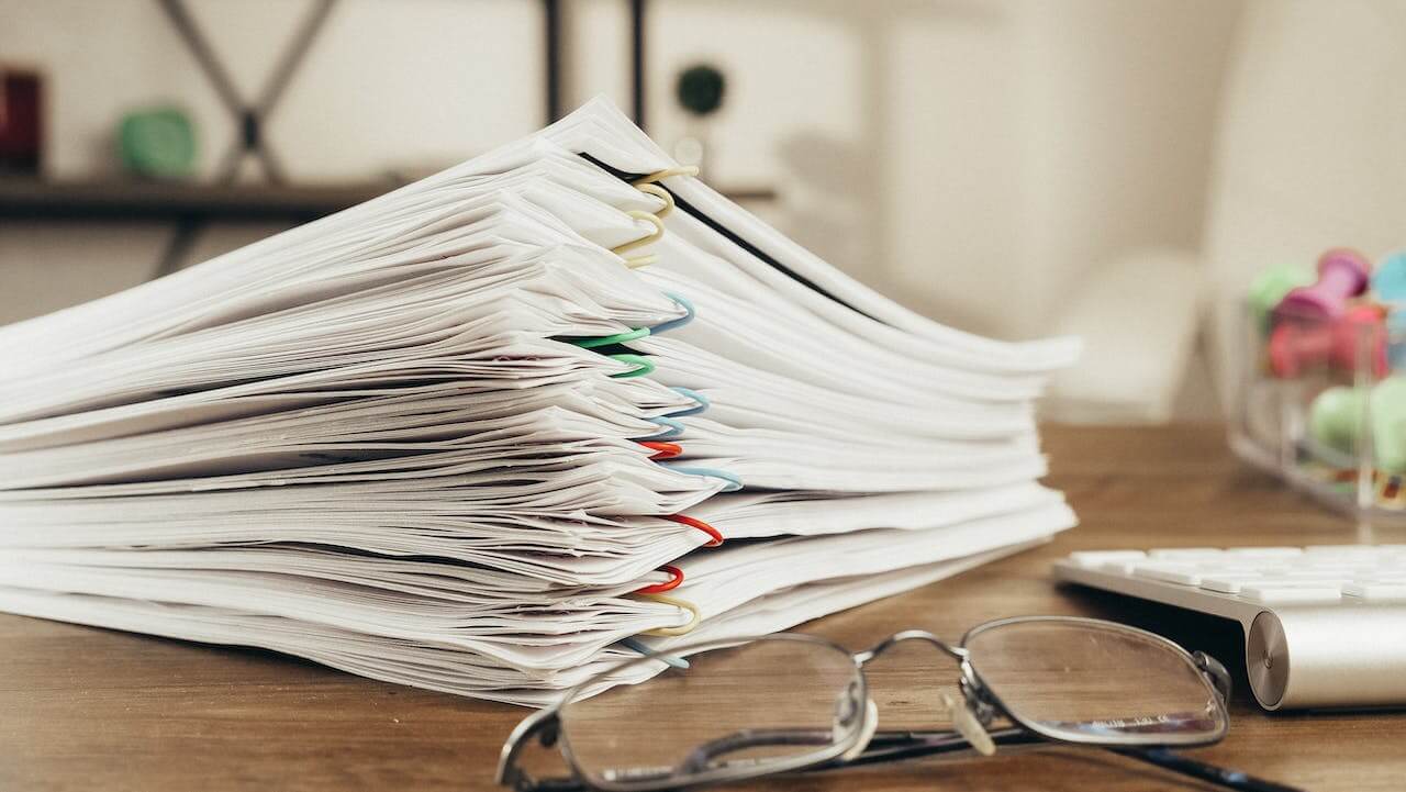 stack of documents resting next to reading glasses on a desk