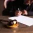 judge writing on paper with gavel in foreground