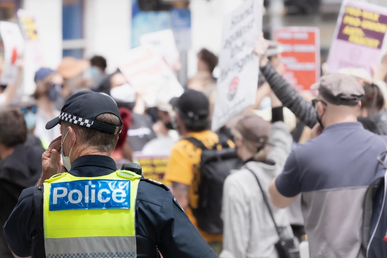 police officer in foreground, protesters in background