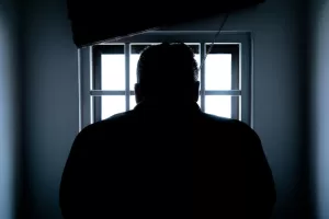 silhouette of man in front of window with bars