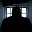 silhouette of man in front of window with bars