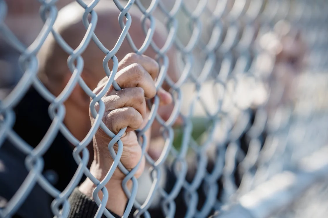 person holding chain link fence