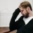 troubled man with hand on forehead sitting in chair