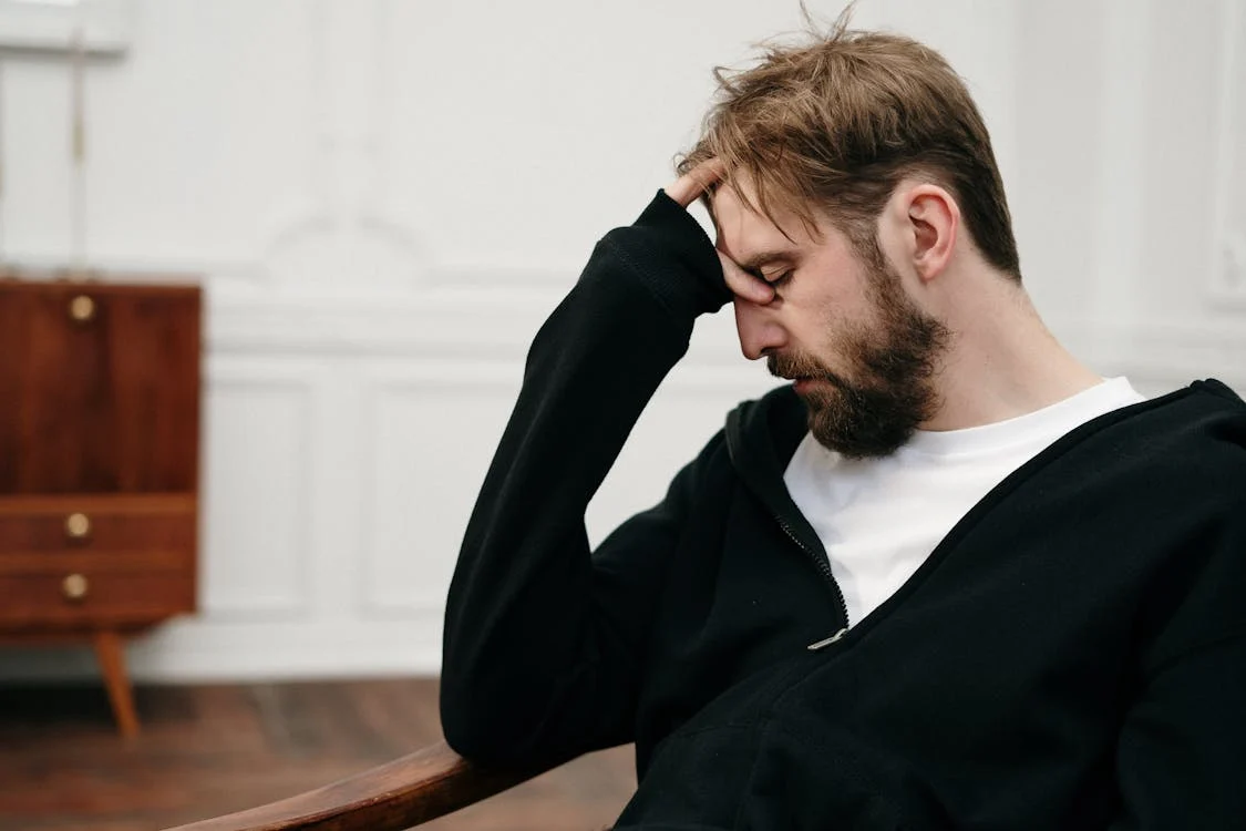 troubled man with hand on forehead sitting in chair