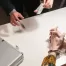 cut-off view of interrogation: handcuffed hands of suspect, investigator holding bags of drugs