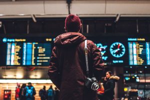 anonymous traveller looking at flight information screens in airport