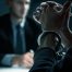 handcuffed criminal suspect in foreground, out of focus lawyer in background