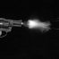 A black and white picture of a small pistol firing