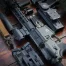 Close-up of tactical firearms and gear arranged on a rustic wooden surface